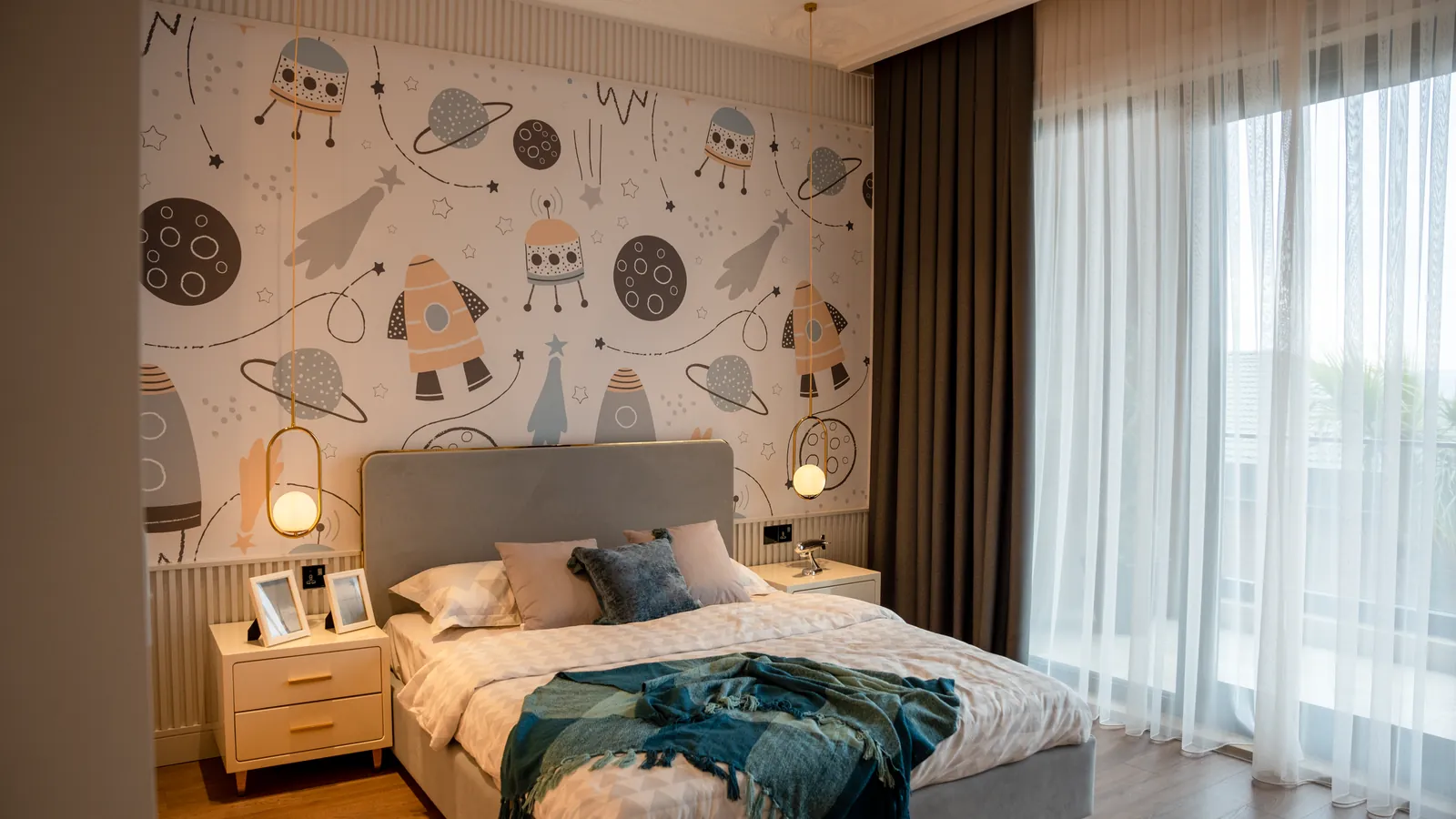 Behang kinderkamer jongen met raketten, planeten en astronauten achter een grijs bed