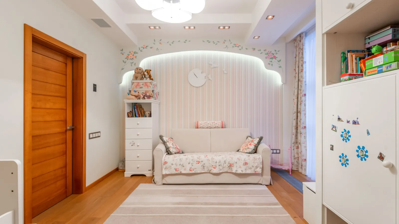Behang kinderkamer met fijn dessin achter een lichte bedbank en wolkenlamp aan het plafond