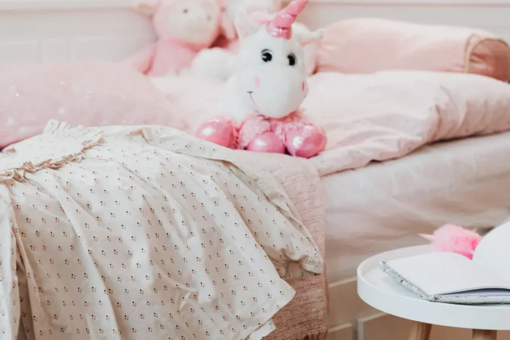 Kinderkamer meisje met zacht roze beddengoed, knuffels en een rond wit bijzettafeltje