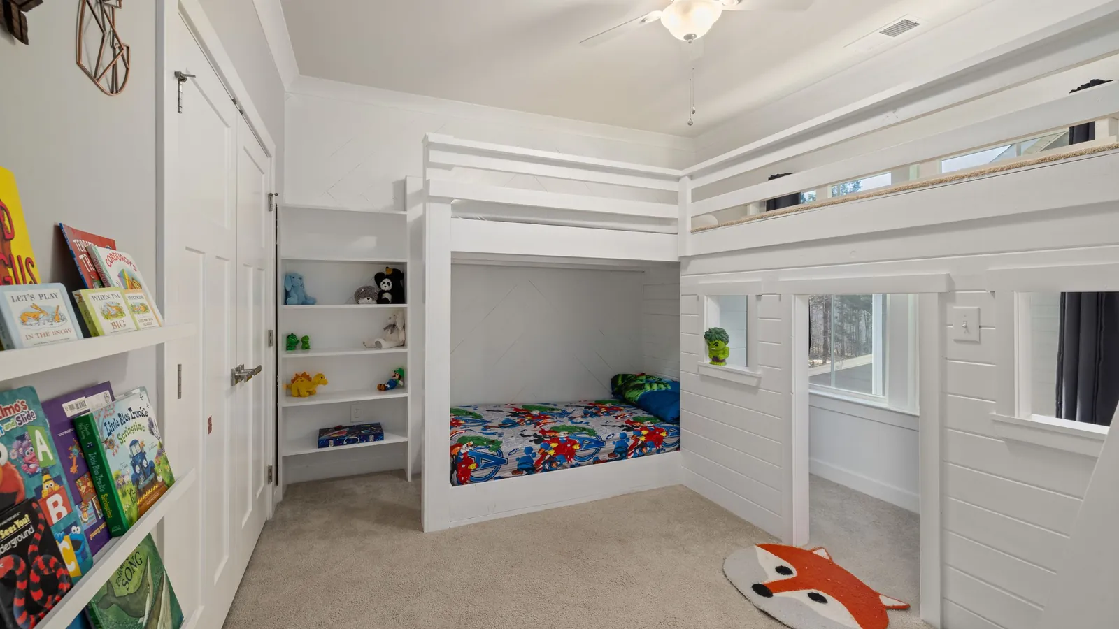 Kleine kinderkamer inrichten met een witte hoogslaper, bed eronder en boekenplanken aan de muur